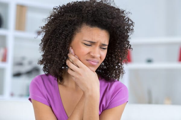 A woman with a jaw injury is sitting on a couch.