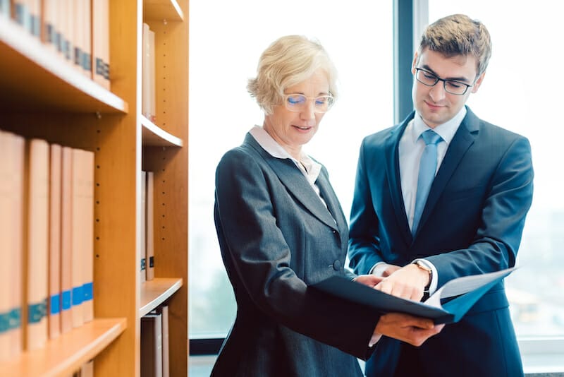 Two attorneys looking at a folder in a law library.